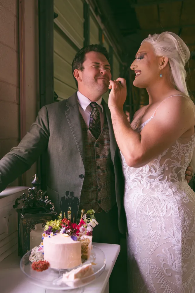 Couple cuts a wedding cake decorated with flowers, smiling and celebrating their special day.