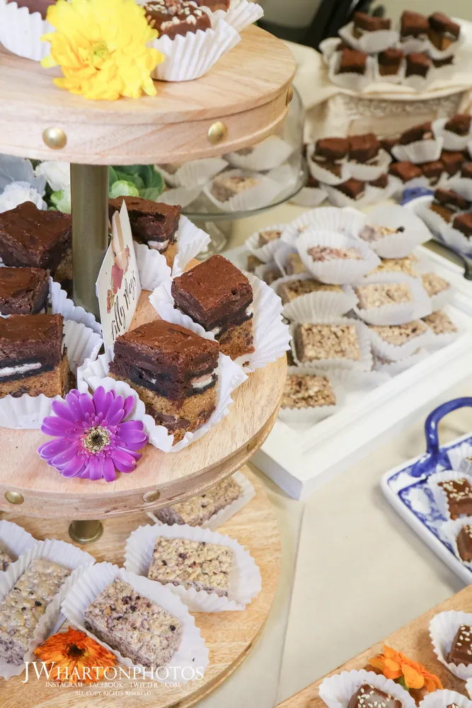 Tiered display of chocolate brownies, dusted with powdered sugar, presented on a cake stand.