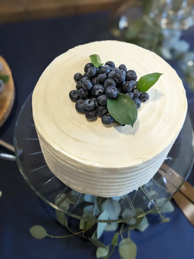 Layer cake with vanilla frosting and fresh blueberries on a cake stand.