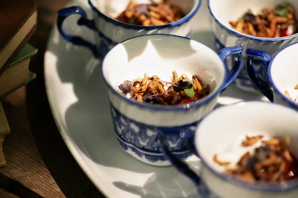 Small porcelain bowls filled with vibrant red chili paste and crispy fried garlic. A close-up food still life.
