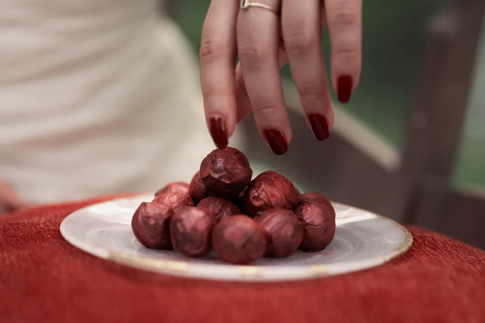 Red velvet truffles on a white plate, held by a hand with red nail polish. Sweet dessert treat.